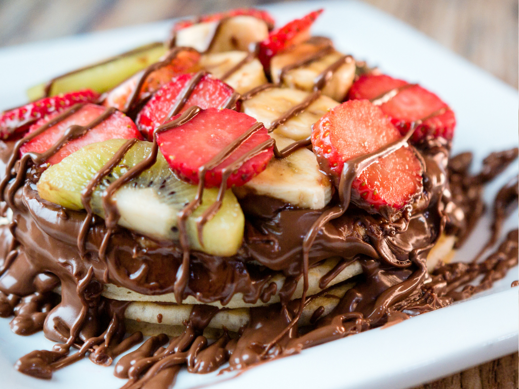 Stack of pancakes topped with strawberries, kiwi, bananas, and rich chocolate drizzle — featured in a kids' dessert cooking class in Chicago, Crest Hill, or Mokena