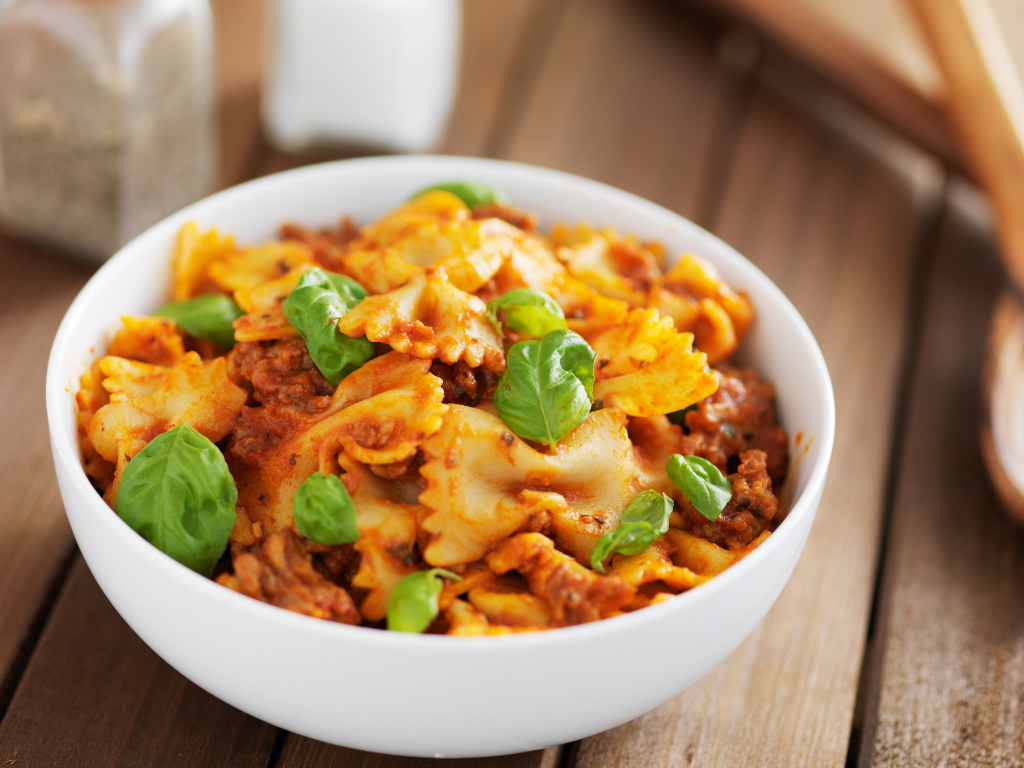 Delicious bowtie pasta in hearty Bolognese sauce garnished with fresh basil—perfect for showcasing Italian cooking class experiences in Mokena, Crest Hill, and Chicago