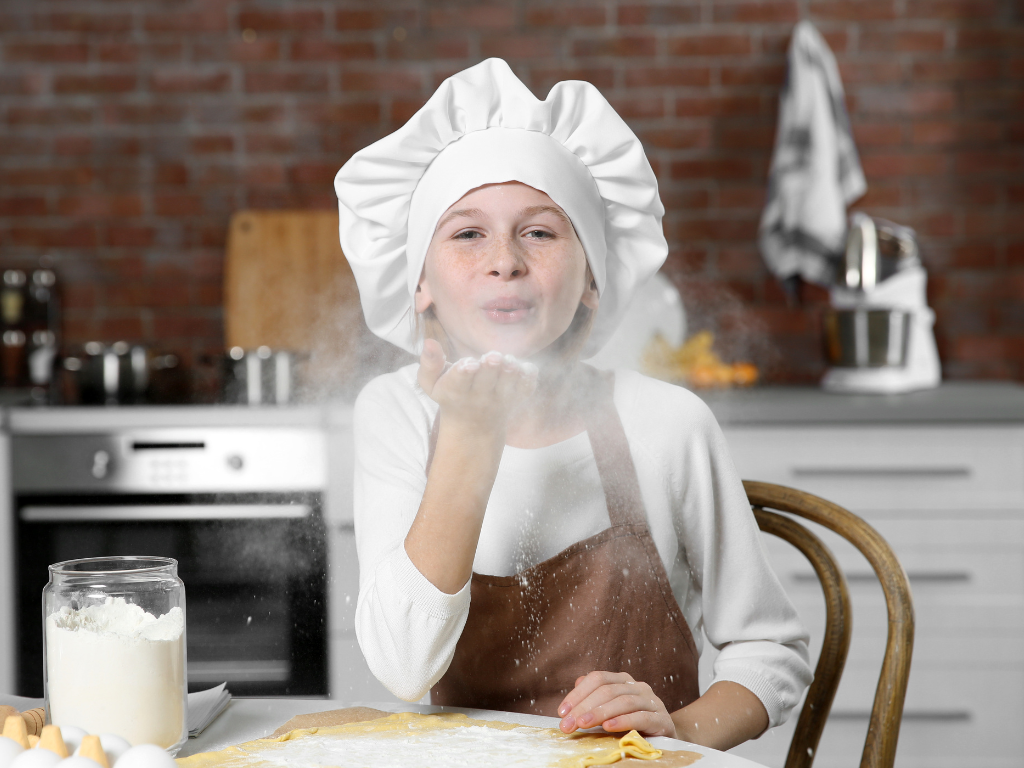 A joyful young chef blows a kiss of flour during a hands-on cooking class—capturing the fun and creativity of kids’ culinary workshops in Mokena, Crest Hill, and Chicago, Illinois