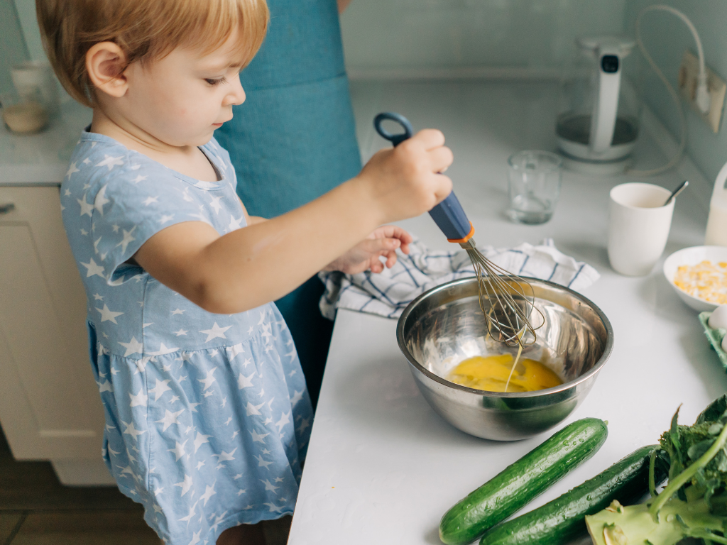 Adorable toddler learning to whisk eggs in a fun kids' cooking class—perfect for families in Mokena, Crest Hill, and Chicago, Illinois looking to spark culinary creativity early