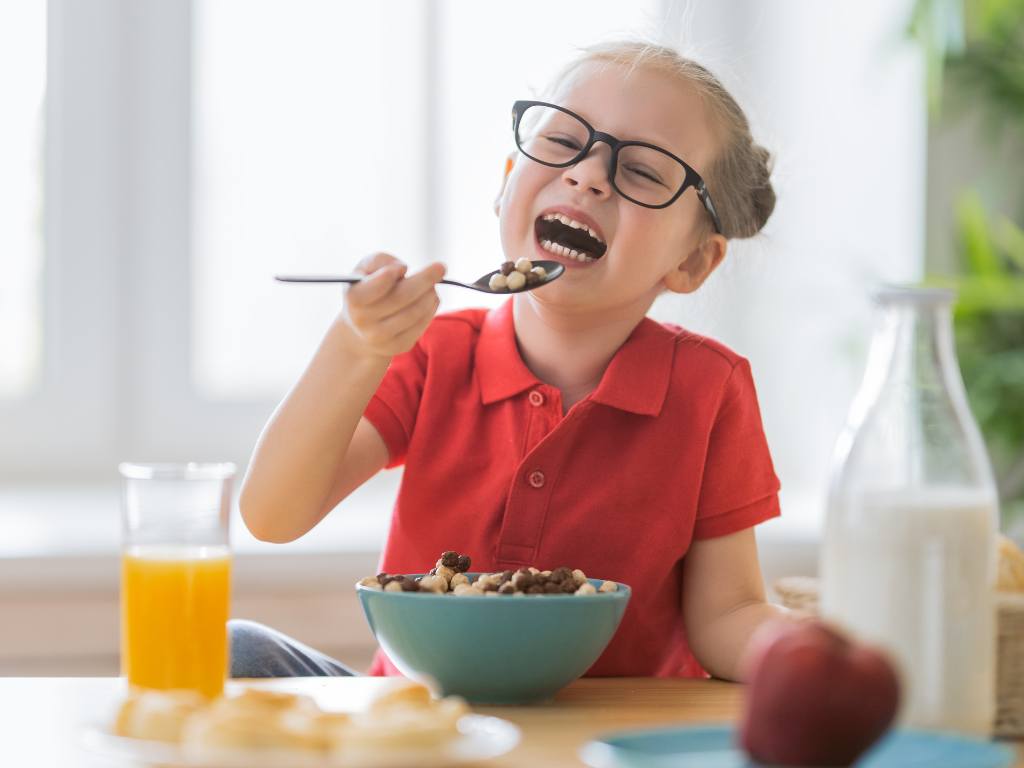 Happy child laughing while eating cereal at a breakfast table, featured in a kids’ cooking class or family-friendly food workshop in Chicago, Crest Hill, or Mokena.