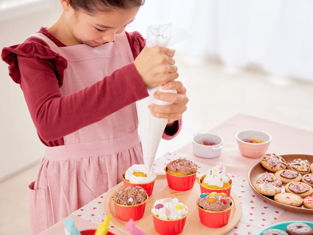 Young girl decorating cupcakes with frosting and sprinkles during a kids cupcake decorating class at Farmhouse Academy near New Lenox, Mokena, and Frankfort, Illinois
