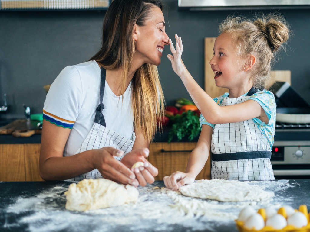 Mother and daughter smiling while baking dough together during a family cooking class at Farmhouse Academy near Tinley Park, Mokena, and Homer Glen, IL