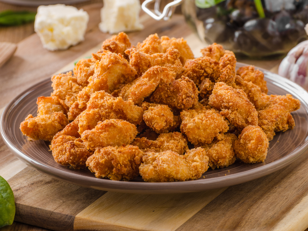 Golden brown, crispy chicken nuggets served on a brown plate, perfect for appetizers, parties, or a tasty homemade snack everyone will love.