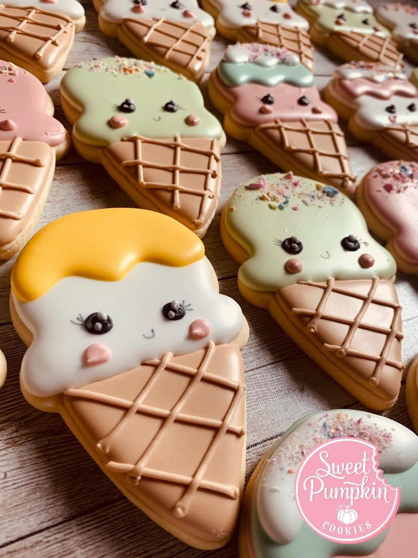 Decorated sugar cookies shaped like smiling ice cream cones with pastel icing and sprinkles, featured in a cookie decorating class in Chicago, Crest Hill, or Mokena.