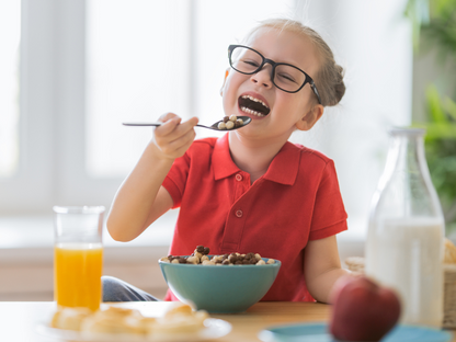 Happy child laughing while eating cereal at a breakfast table, featured in a kids’ cooking class or family-friendly food workshop in Chicago, Crest Hill, or Mokena.