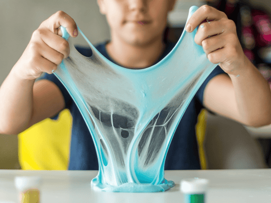 Child stretching bright blue slime during a slime-making and sensory play class at Farmhouse Academy near Romeoville, Lockport, and Plainfield, Illinois