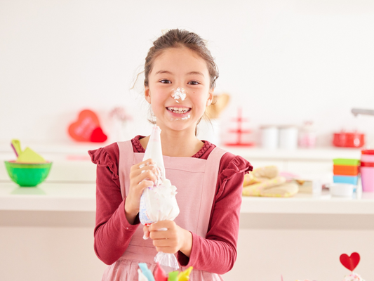 A joyful young girl decorates cookies with frosting during a  kids' baking class in Mokena, Crest Hill, and Chicago, Illinois. Sweet fun and hands-on learning for all ages